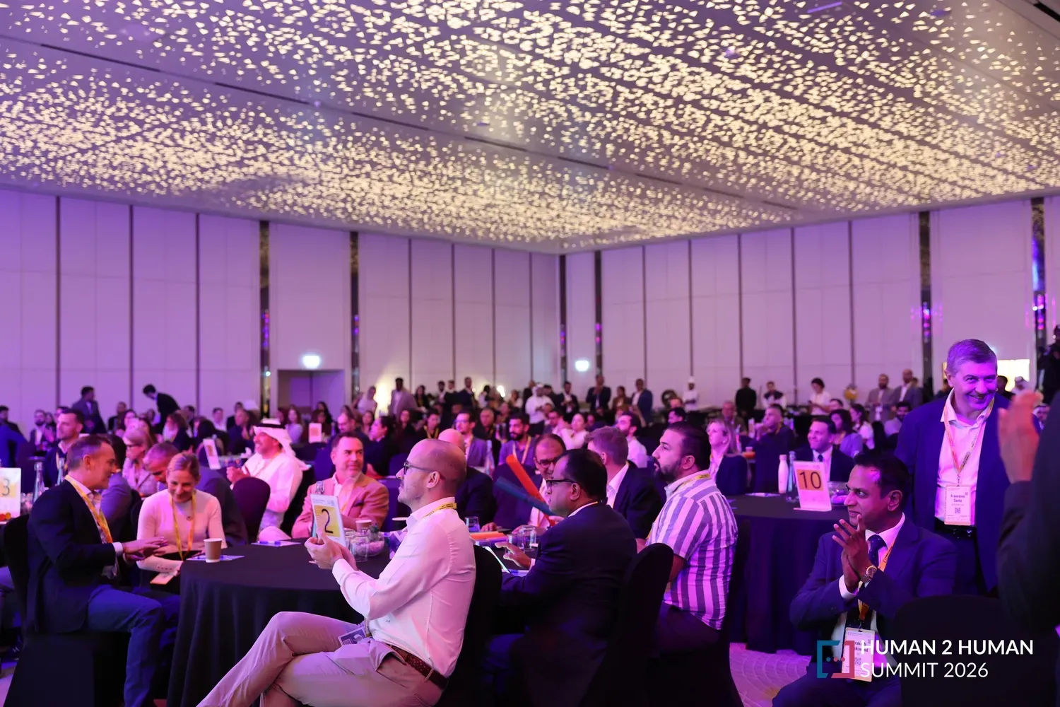 A wide view of the full ballroom, the audience applauding