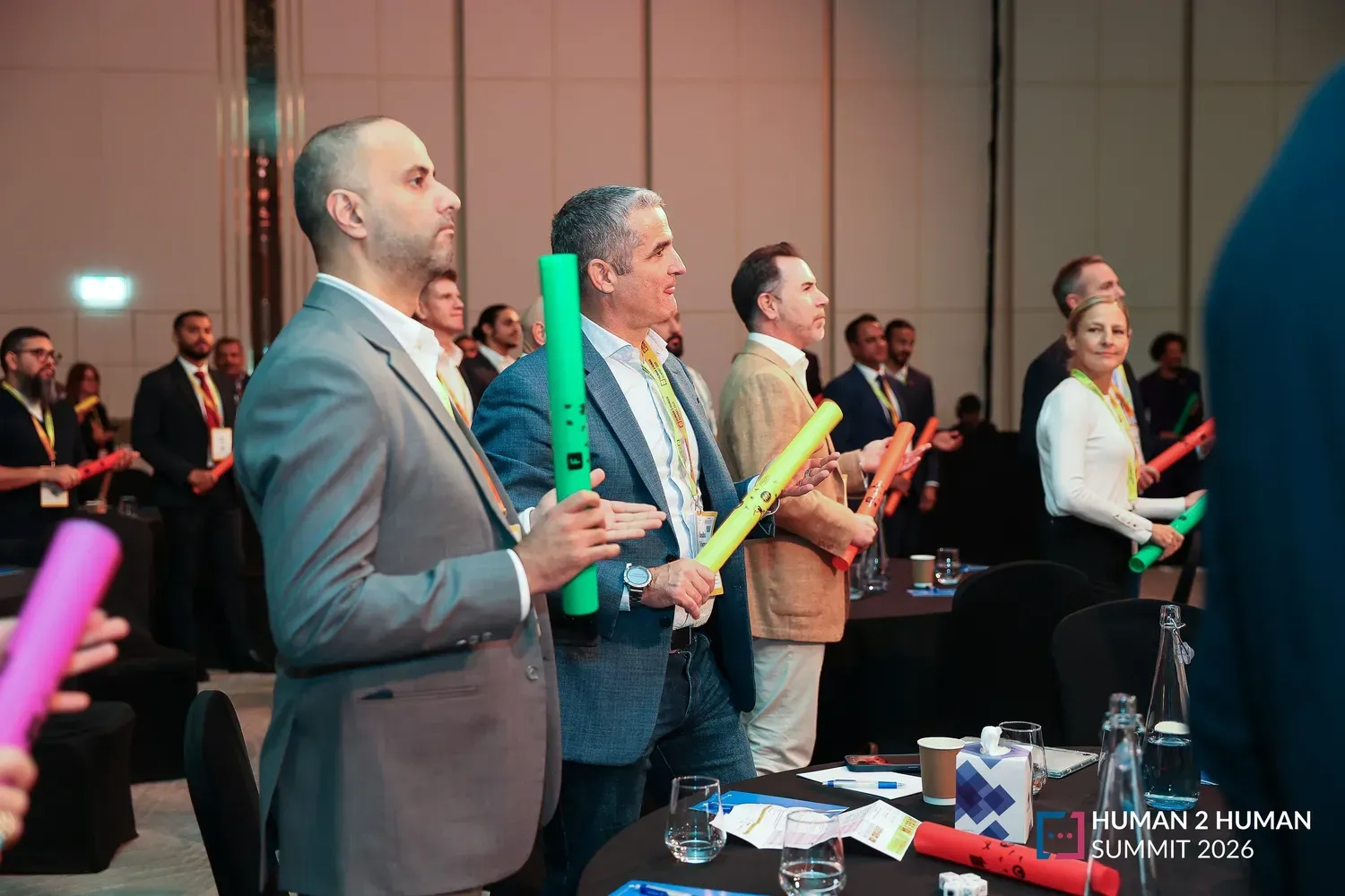 Attendees standing at their tables holding colourful percussion tubes during an interactive musical session